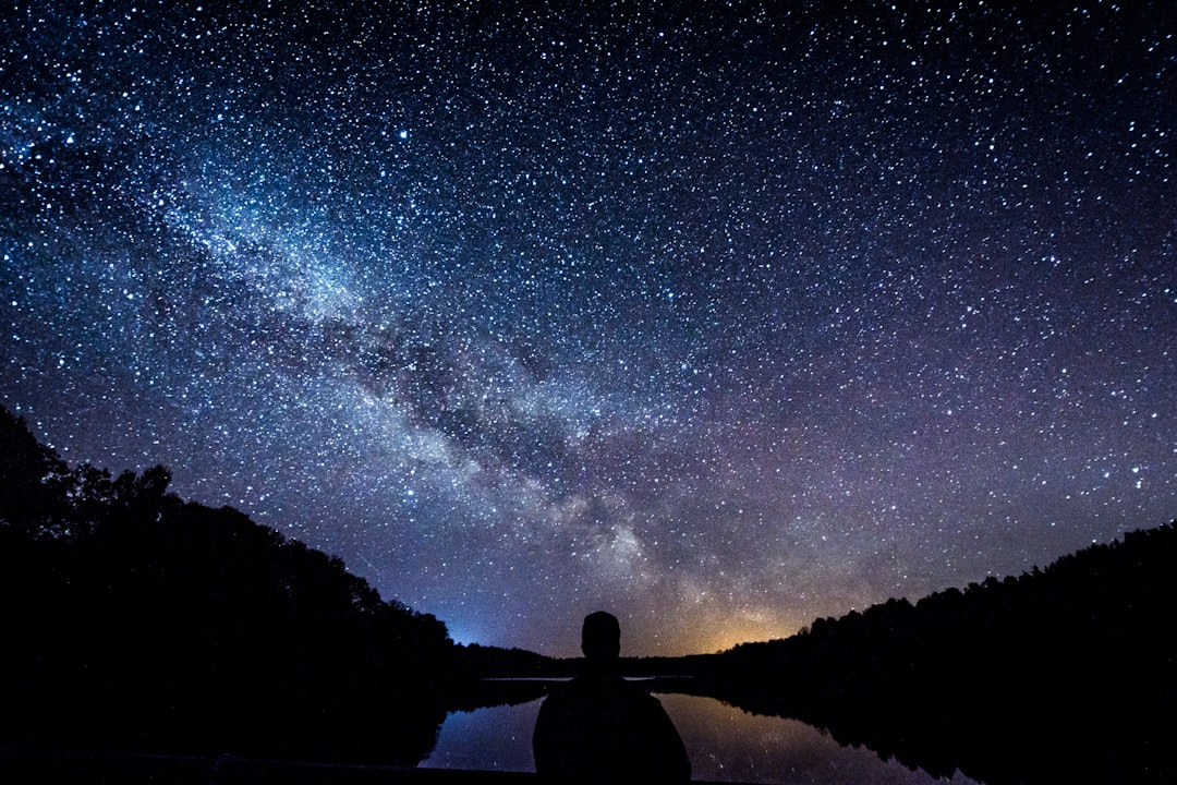 silhouette of person standing under starry sky