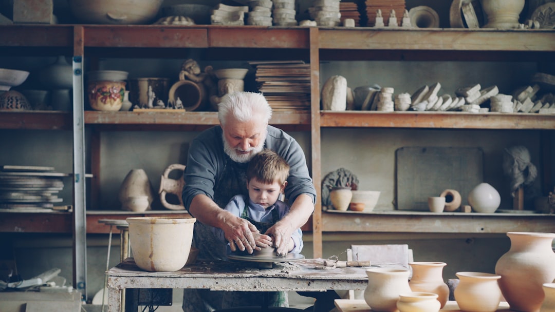 Grandfather teaches a boy pottery.